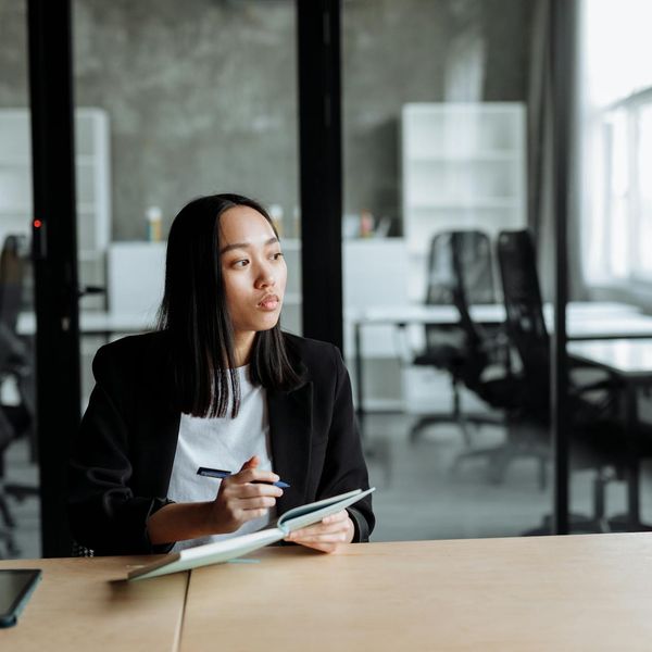 A person sitting comfortably at a modern desk and looking out the window thoughtfully.